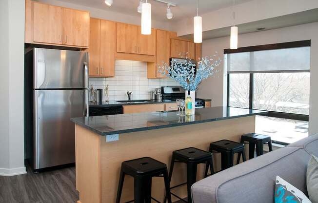 A kitchen with a refrigerator, stove, and bar stools.