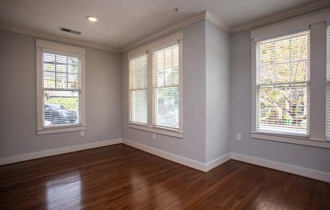 A room with wooden floors and three windows.