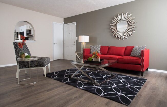 A living room with a red couch, a chair, and a coffee table at Ridge Crossings Apartments, Hoover, AL