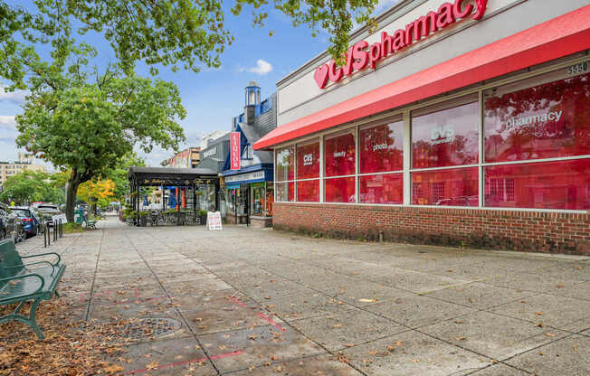 A red and white pharmacy with a green bench in front.