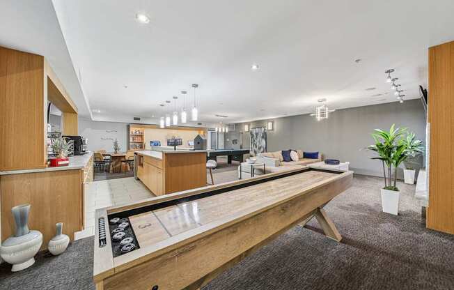 A shiny wooden table is in the middle of a carpeted room with a bowling alley.