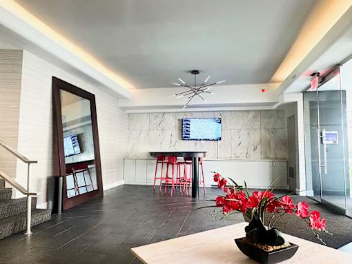 A modern living room with a wooden table and a vase of red flowers.