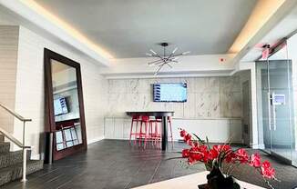 A modern living room with a wooden table and a vase of red flowers.