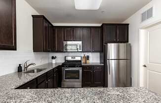 A kitchen with dark wood cabinets and granite countertops.