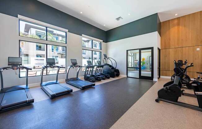 A gym with treadmills, elliptical machines, and a weight machine.