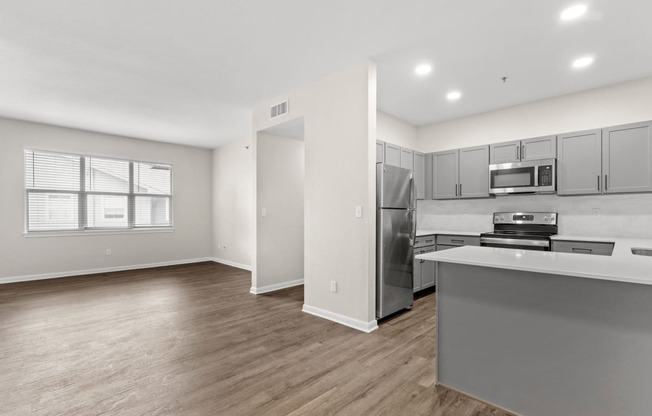 the living room and kitchen of an apartment with stainless steel appliances at Switchback on Platte Apartments, Littleton, CO 80120