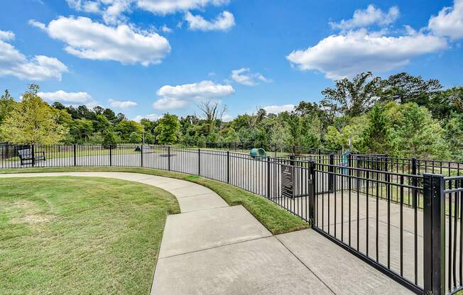 a park with a black fence and a sidewalk and grass