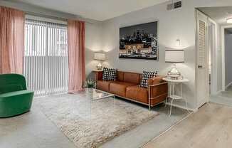 A living room with a green chair, a brown sofa, and a white side table.
