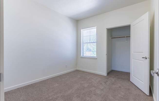 A room with a carpeted floor and a window with blinds at Riverplace Apartment Homes, Independence, OR