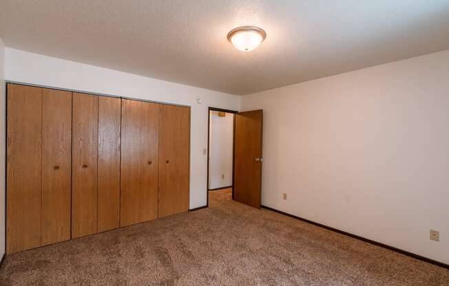 A spacious bedroom with carpeted floors a large closet. Fargo, ND Long Island Apartments.