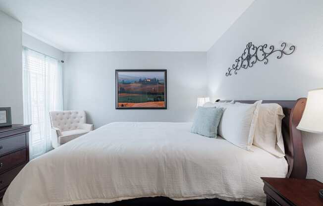 a bedroom with a large white bed and a painting on the wall