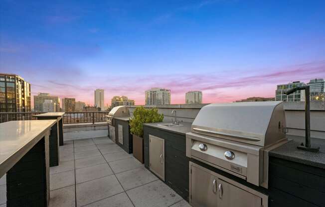 the city skyline as seen from the roof deck of a building with an outdoor grill