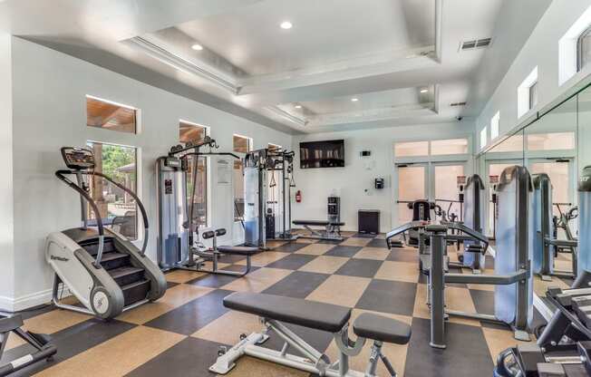 a gym with weights and cardio equipment and glass walls