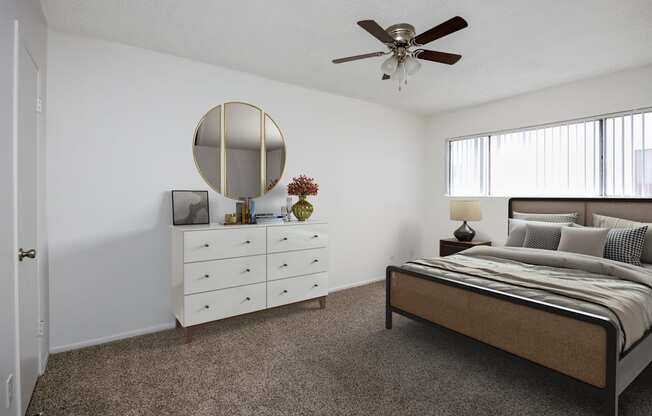 a bedroom with a bed and a white dresser and a ceiling fan