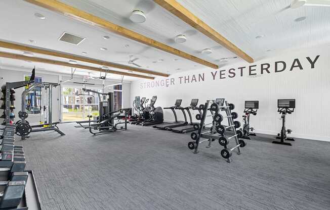 A gym with a variety of equipment and a sign that says "STRONGER THAN YESTERDAY".