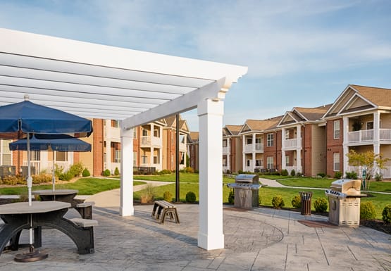 Grilling area with picnic tables and umbrellas under a pergola