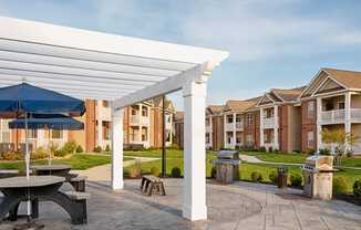 Grilling area with picnic tables and umbrellas under a pergola