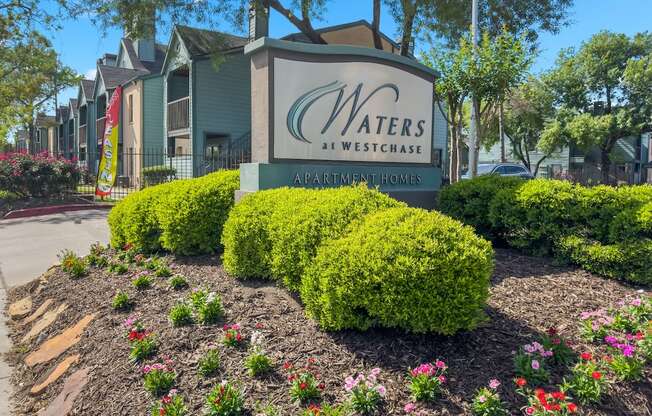 a sign for waters at westchase in front of some flowers and bushes