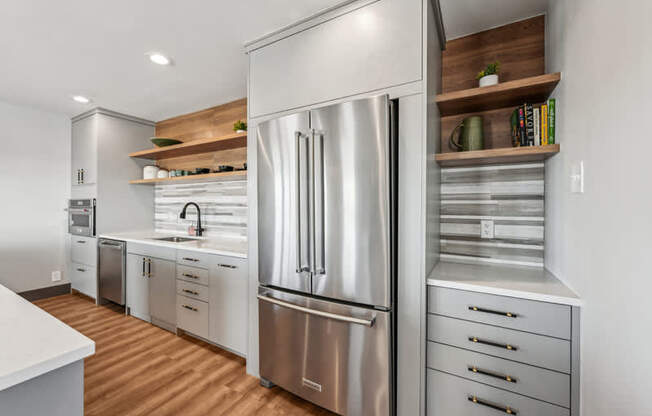 A modern kitchen with a stainless steel refrigerator and wooden shelves.