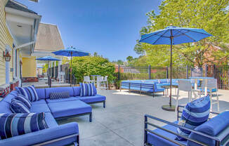 Outdoor patio with blue couches and umbrellas at Windsor Ridge at Westborough, Westborough, MA