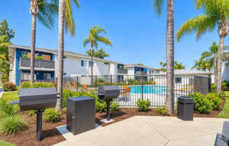 A sunny day at a residential complex with a pool and palm trees.