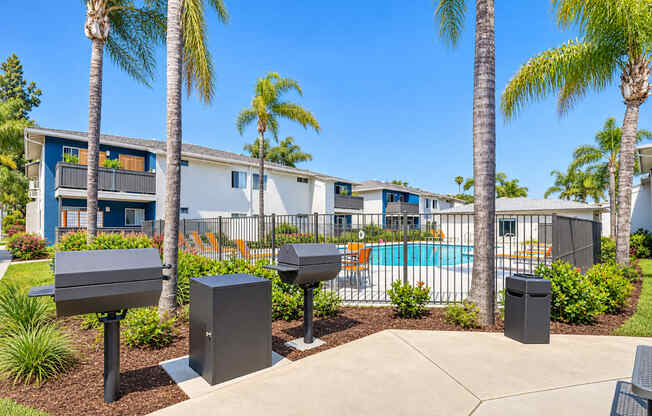 A sunny day at a residential complex with a pool and palm trees.