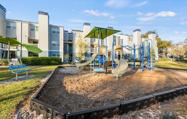 an outdoor playground with slides and swings at an apartment complex