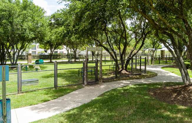 A park with a walking path and a fence.