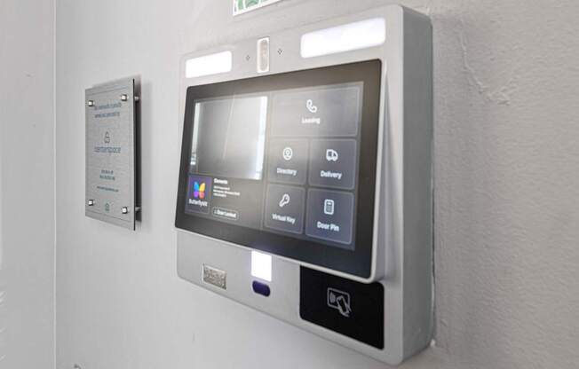 A wall-mounted control panel with a screen and buttons for various functions.