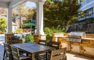 a patio with a table and chairs and a grill