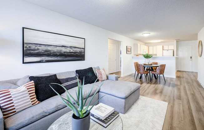 A living room with a grey couch and a painting on the wall.