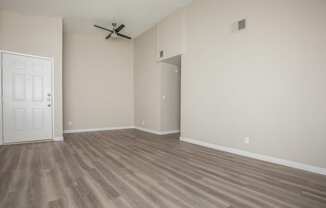 an empty living room with a ceiling fan