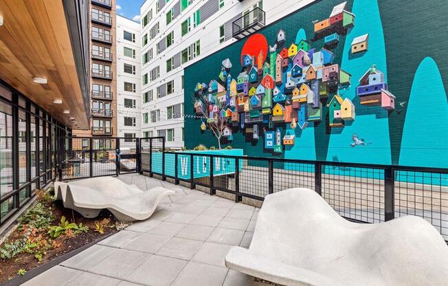 a large mural on the side of a building with two benches in front of it