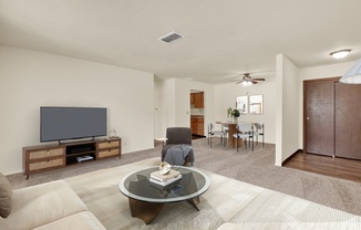 A living room with a television, a glass coffee table, and a brown sofa.