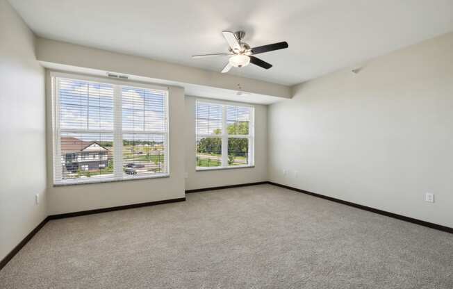 the living room of a home with large windows and a ceiling fan