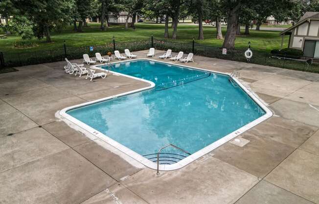 a swimming pool with chaise lounge chairs and trees in the background at Beacon Hill and Great Oaks Apartments, Illinois, 61109