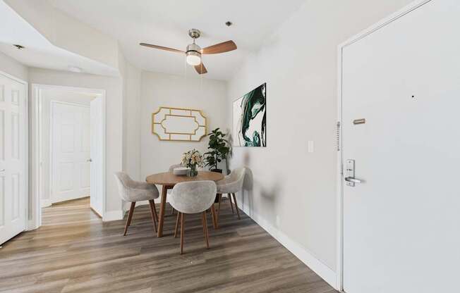 A dining room with a table set for two and a ceiling fan.