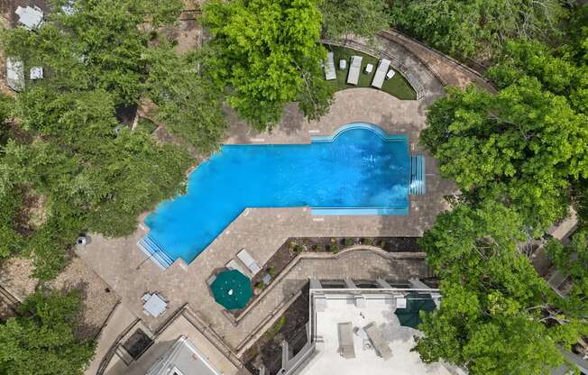 A swimming pool surrounded by trees and a building.