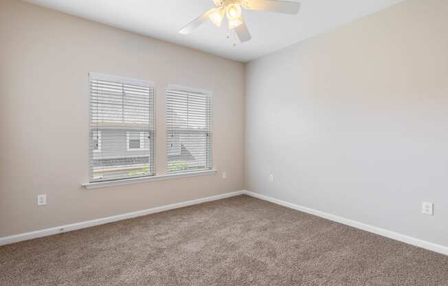 an empty bedroom with a ceiling fan and a window