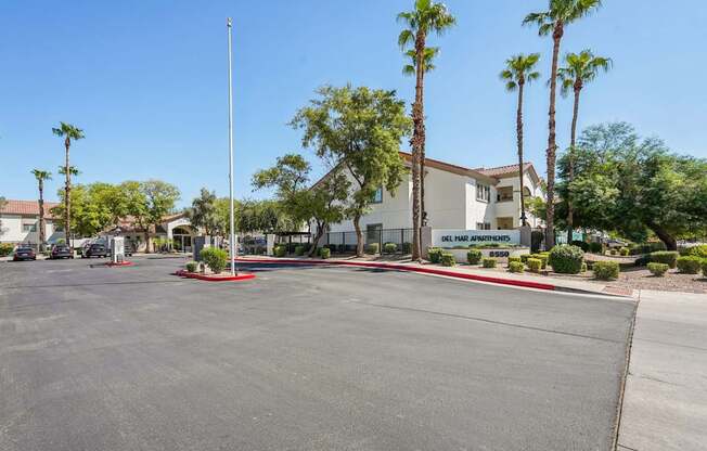A parking lot with a building and palm trees in the background.