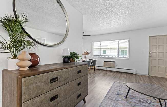 a living room with a dresser and a round mirror