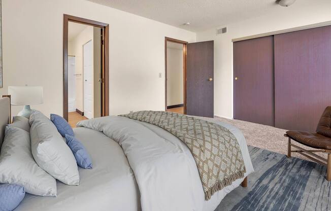 A bedroom with a large bed and a chair.