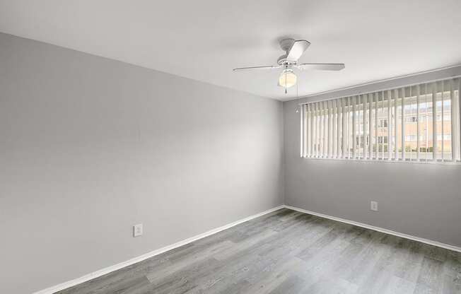 an empty bedroom with a window and a ceiling fan