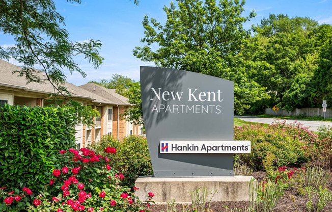 A sign for New Kent Apartments by Hankin Apartments stands in front of a building.