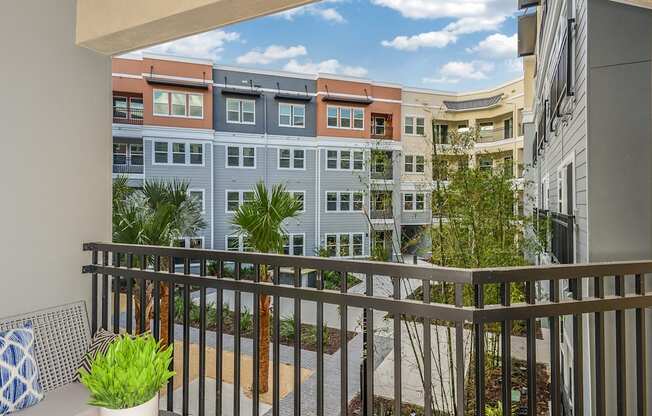 A balcony with a potted plant and a pillow on the left.