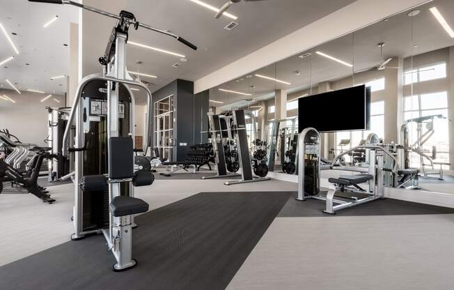 a large fitness room with a large screen tv on the wall and various exercise equipment on the