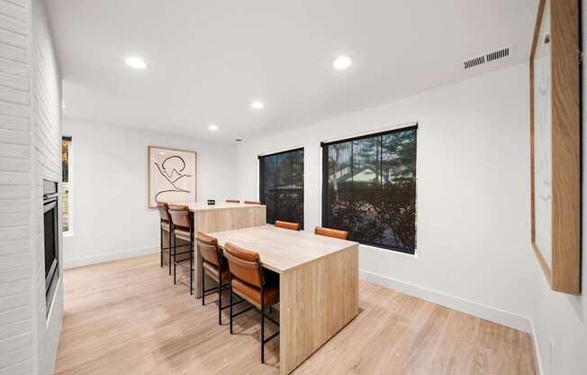 A long wooden table with chairs is in a white room.