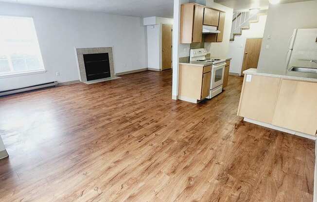 an empty living room and kitchen with wood flooring