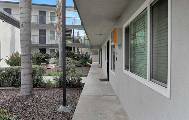 A long concrete walkway leads to a building with a balcony.