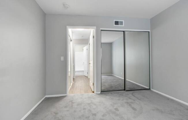 an empty bedroom with mirrored closet doors and a carpeted floor